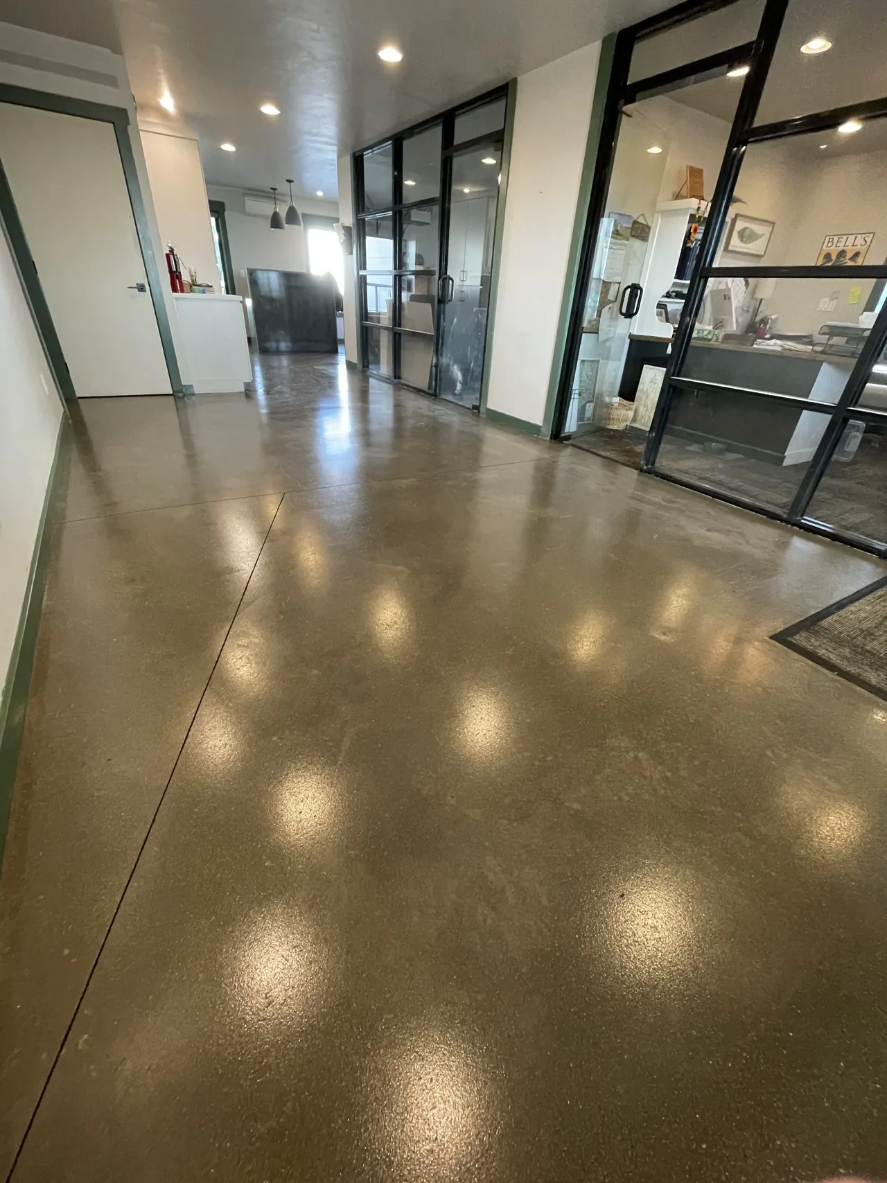 Brown-toned concrete floor along a corridor with glass office walls